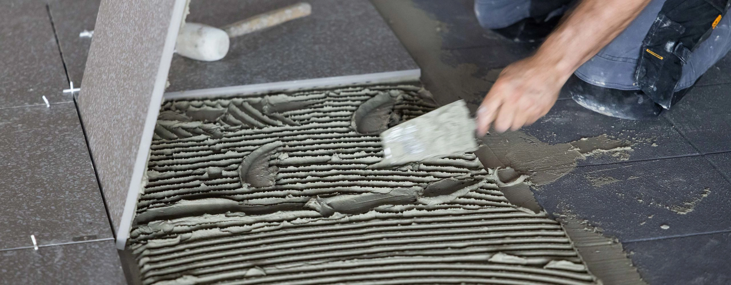 Application d'un mortier-colle haute performance et pose de carrelage en double encollage par un artisan de Millius Groupe