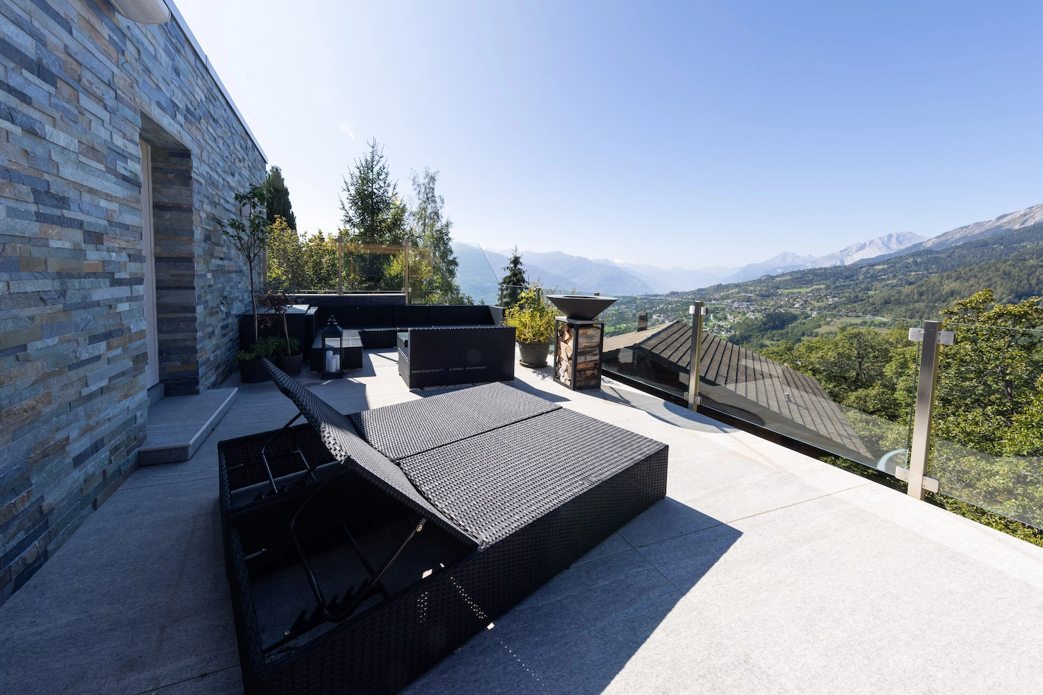 Réalisation d'une terrasse extérieure en carrelage grand format à Icogne, offrant une vue panoramique sur la plaine du Rhône en Valais